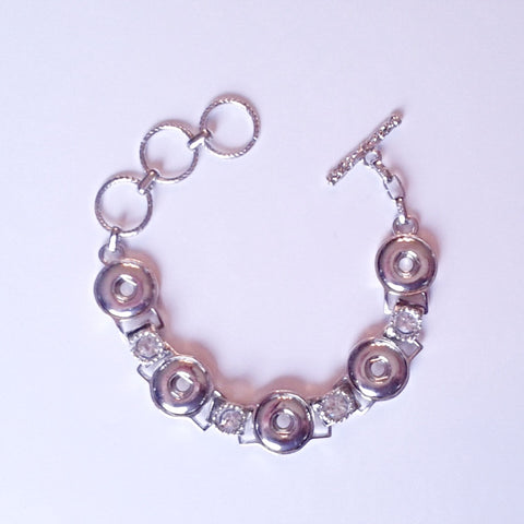 Silver coloured bracelet with rhinestones in between snap links that fits five 12 mm snaps